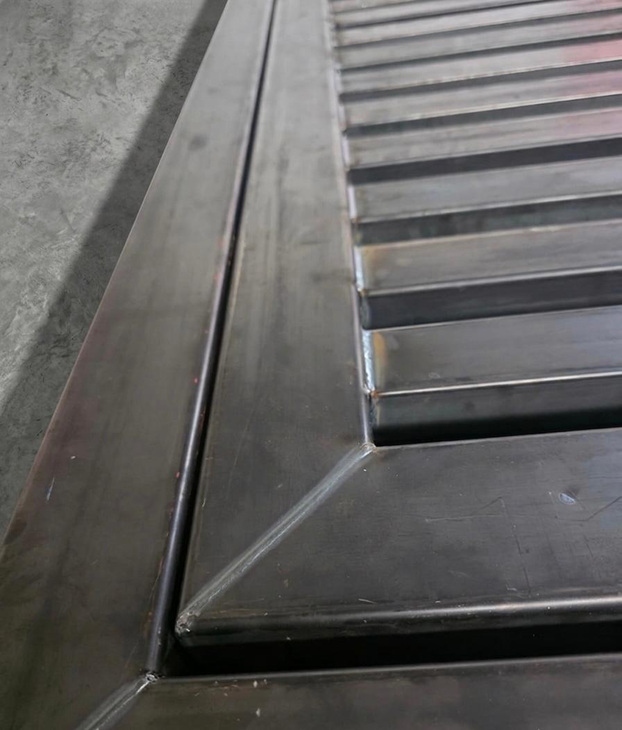 Close-up of a clean laser-welded corner joint on a slatted steel panel