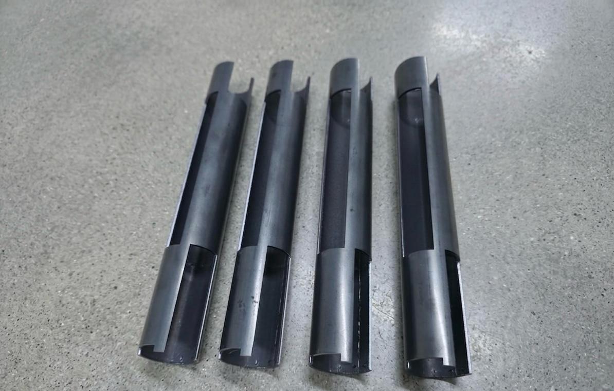 Four steel tube sections with curved, notched scoop-cut ends
