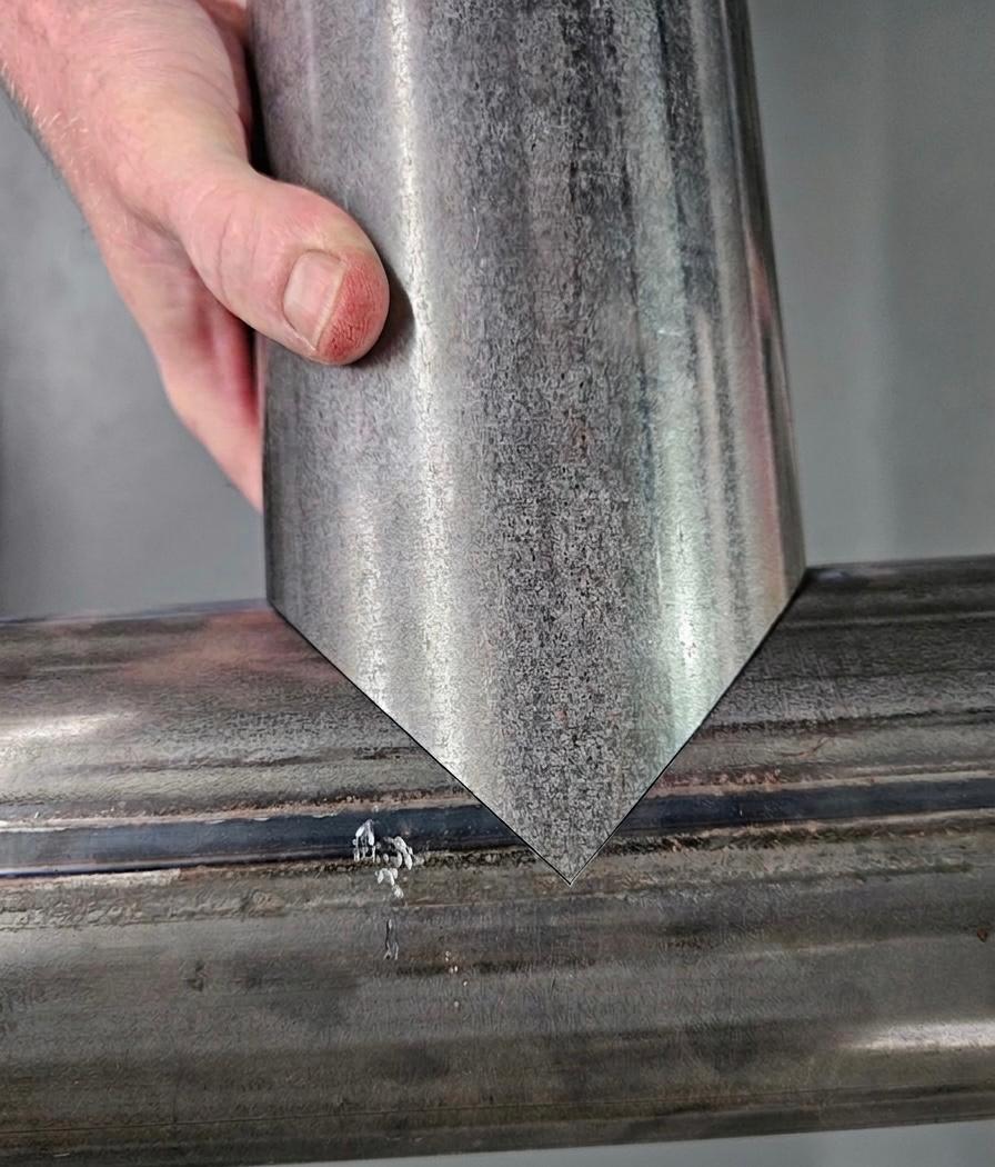 Close-up of a hand holding a laser-cut steel tube with a precise mitred point